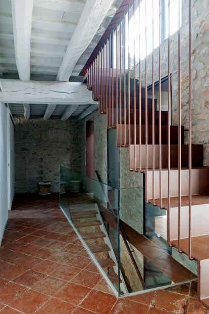 La escalera transparente, de acero corten y peldaños de madera, que está adosada al patio, lleva a la primera planta, donde se encuentran las habitaciones. 