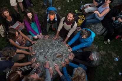 Varias personas forman un círculo con sus manos sobre una de las rocas del monumento Stonehenge en Wiltshie, al sur de Inglaterra.