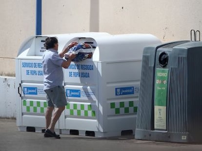 Un vecino deposita ropa en el contenedor municipal.