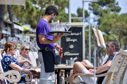Un camarero atiende a unos clientes en la terraza de un restaurante del paseo marítimo de Platja d'Aro (Girona).