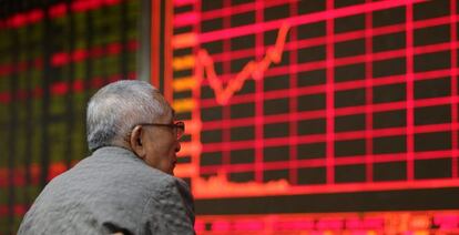 Un inversor de valores observa una pantalla que muestra el &iacute;ndice en la Bolsa de Hong Kong. 