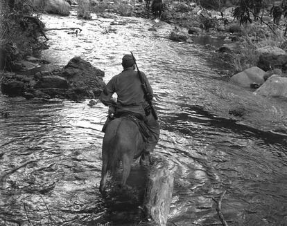 El guerrillero Fidel Castro, de espaldas, cruza a caballo el río Yara, en Sierra Maestra.