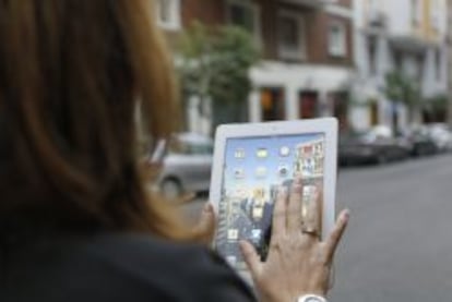 Una mujer utiliza una tablet mientras pasea por la calle. 