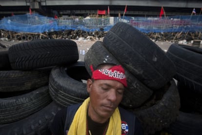 Un <i>camisa roja</i> duerme sobre uno de los muros de neumáticos que  la oposición ha utilizado para levantar barricadas en Bangkok.