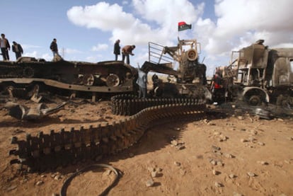Un grupo de curiosos revisa los tanques del Ejército libio dañados tras un bombardeo de la coalición aliada, en la carretera entre Bengasi y Ajdabiya.