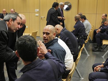 Los abogados discuten con los cuatro acusados del motín de Picassent al inicio del juicio.
