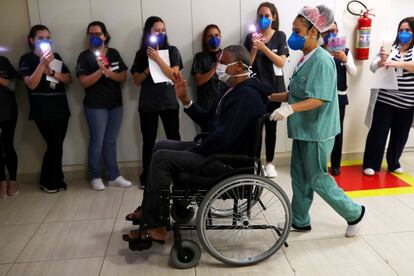 Varios sanitarios encienden las linternas de sus teléfonos en honor a José Queiroz dos Santos (en silla de ruedas), de 62 años, que es dado de alta tras sobrevivir al coronavirus en el Hospital Municipal de Parelheiros, en São Paulo (Brasil).