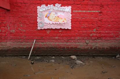 Un signo de ducha cuelga de una pared de una vivienda, Carapongo Huachipa, Lima.