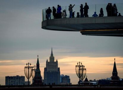 Turistas sobre un puente en el parque Zaryadye con el Kremlin y el Ministerio de Exteriores al fondo en Moscú (Rusia).