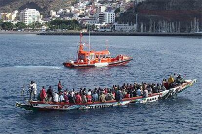 Una gran piragua con 103 ocupantes llega al puerto de San Sebastián de la Gomera escoltada por un barco de Salvamento Marítimo.