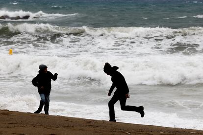 Dos jóvenes juegan en la playa de Barcelona durante el último temporal de viento, en una imagen de archivo.