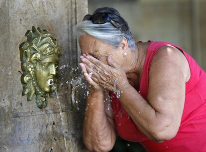 Una mujer se refresca en una fuente de Valencia, para poder soportar el calor.