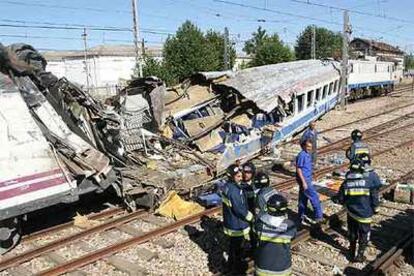 Un grupo de bomberos junto al vagón que resultó más afectado en el accidente.