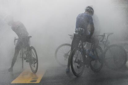 Varios ciclistas se refrescan con el agua lanzada por bomberos tras cruzar la línea de meta, en la quinta etapa de la carrera ciclista malaya Le Tour de Langkaw, en Taiping.