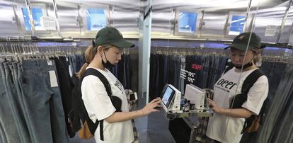 Una cliente de una tienda de ropa consulta detalles en una tableta durante una compra.