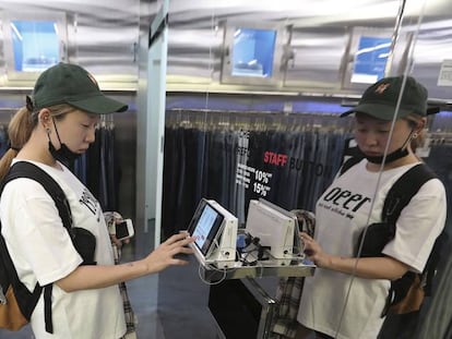 Una cliente de una tienda de ropa consulta detalles en una tableta durante una compra.