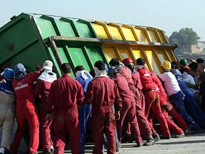 Un grupo de trabajadores vuelca un contenedor en las protestas de la factoría de astilleros en Sevilla.