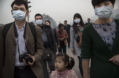 Varias personas caminan con mascarilla por la plaza de Tiananmen de Pek&iacute;n.