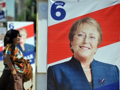 Una mujer camina al lado de la propaganda pol&iacute;tica de Bachelet. 