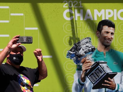 Un fan se hace una foto ante un cartel de Novak Djokovic en Melbourne (Australia).