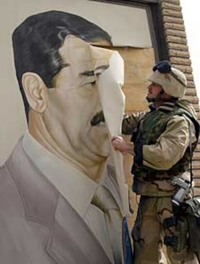 Un <b><i>marine </b></i>estadounidense arranca un retrato de Sadam, en la ciudad iraquí de Safwan.