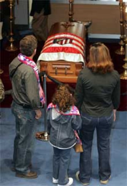 Aficionados rojiblancos pasan junto al féretro de Jesús Gil en la capilla ardiente instalada en el Calderón.