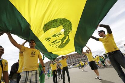 Torcedores carregam uma bandeira com uma imagem de Pelé.