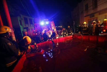 Bombeiros pegam água em um tanque para combater o fogo em um dos morros afetados pelo incêndio.