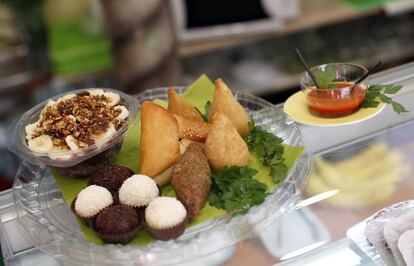 En el plato hondo de plástico está el 'açaí' servido con plátano y granola. Enfrente están los 'brigadeiros' de chocolate y los 'beijinhos' de coco. Ambos son postres típicos de Brasil. Al lado están las 'coxinhas' -croqueta de patata, trigo y pollo-, el 'quibe' -empanadillas-.