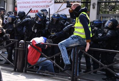 Policiais batem em manifestante envolto em uma bandeira francesa durante manifestações em Paris.