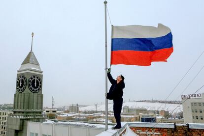 Un trabajador coloca a media asta la bandera rusa en un edificio gubernamental en Krasnoyarsk (Rusia). Los buzos militares rusos hallaron el fuselaje del avión Tu-154 que se estrelló en el mar Negro con 92 personas a bordo minutos después de despegar del aeropuerto de Sochi rumbo a Siria.