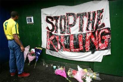 Un hombre con la camiseta brasileña observa la fotografía del hombre muerto cerca de la estación de Stockwell.