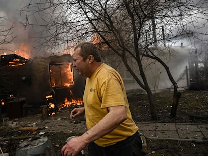 Yevghen Zbormyrsky, 49, runs in front of his burning house after being shelled in the city of Irpin, outside Kyiv, on March 4, 2022. - More than 1.2 million people have fled Ukraine into neighbouring countries since Russia launched its full-scale invasion on February 24, United Nations figures showed on March 4, 2022. (Photo by Aris Messinis / AFP)