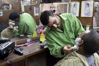 Un barbero iraquí afeita a un cliente en Kerbala, al sur de Bagdad, en 2002.