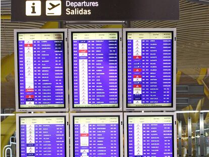 Un hombre tumbado detrás de los paneles de salidas de la T-4 del aeropuerto de Barajas (Madrid).