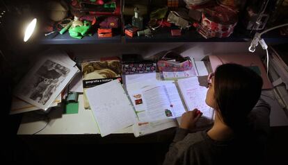 Una adolescente hace los deberes en la habitación de su casa.
