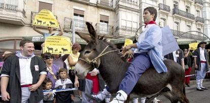 Un participante en la carrera de burros este jueves en Vitoria pasa por delante de las personas que protestaban por el maltrato a los animales