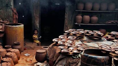 Un niño sentado en la entrada de un taller de cerámica, en Bombay (India).