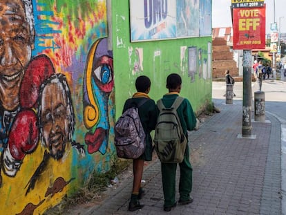 Dos estudiantes caminan frente a un mural de Nelson Mandela, este martes en Johannesburgo.