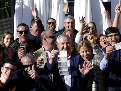 Manuel González, en el centro con cinco décimos, este domingo festejando el cuarto premio de la Lotería de Navidad en Utrera.