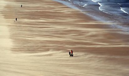 Varias personas caminan por la playa de Tynemouth, en la costa noreste de Inglaterra, afectada por fuertes vientos que atraviesan la región.