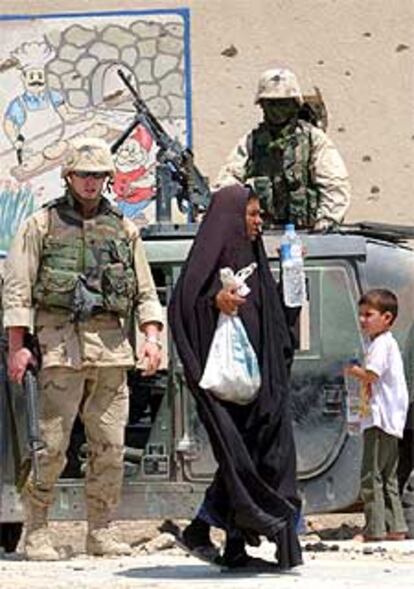 Una mujer iraquí pasa ante dos <i>marines</i> que patrullan a las afueras de Nasiriya.