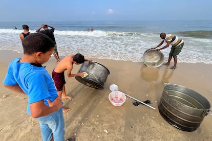 Un niño y un hombre palestinos lavaban ollas el jueves en una playa de Gaza ante la falta de agua potable.