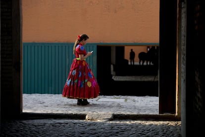 Una mujer charra, conocida como amazona y miembro de una escaramuza, revisa su teléfono durante una competición en la Ciudad de México. Las escaramuzas, a diferencia de los charros, montan de lado.