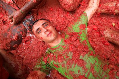 Un hombre yace cansado en el suelo de una calle de Buñol, cubierto de tomate durante la fiesta popular de la Tomatina.
