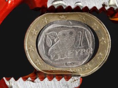 Moneda de un euro griega, aplastada por unas tenazas.
