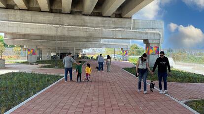 Algunas personas pasean por la zona con planteles del Parque Urbano El Dique, bajo la Autopista Siervo de la Nación (México).