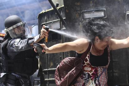 Un policía brasileño rocía con gas a una manifestante durante una protesta, en Río de Janeiro (Brasil).