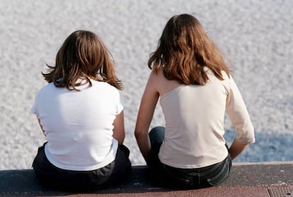  Dos chicas, sentadas en un paseo mar&iacute;timo. 