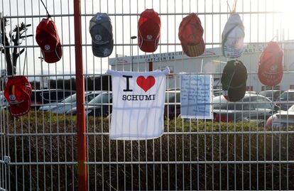 Camisetas e bonés com mensagens de ânimo para Schumacher penduradas em uma grade no Hospital de Grenoble.